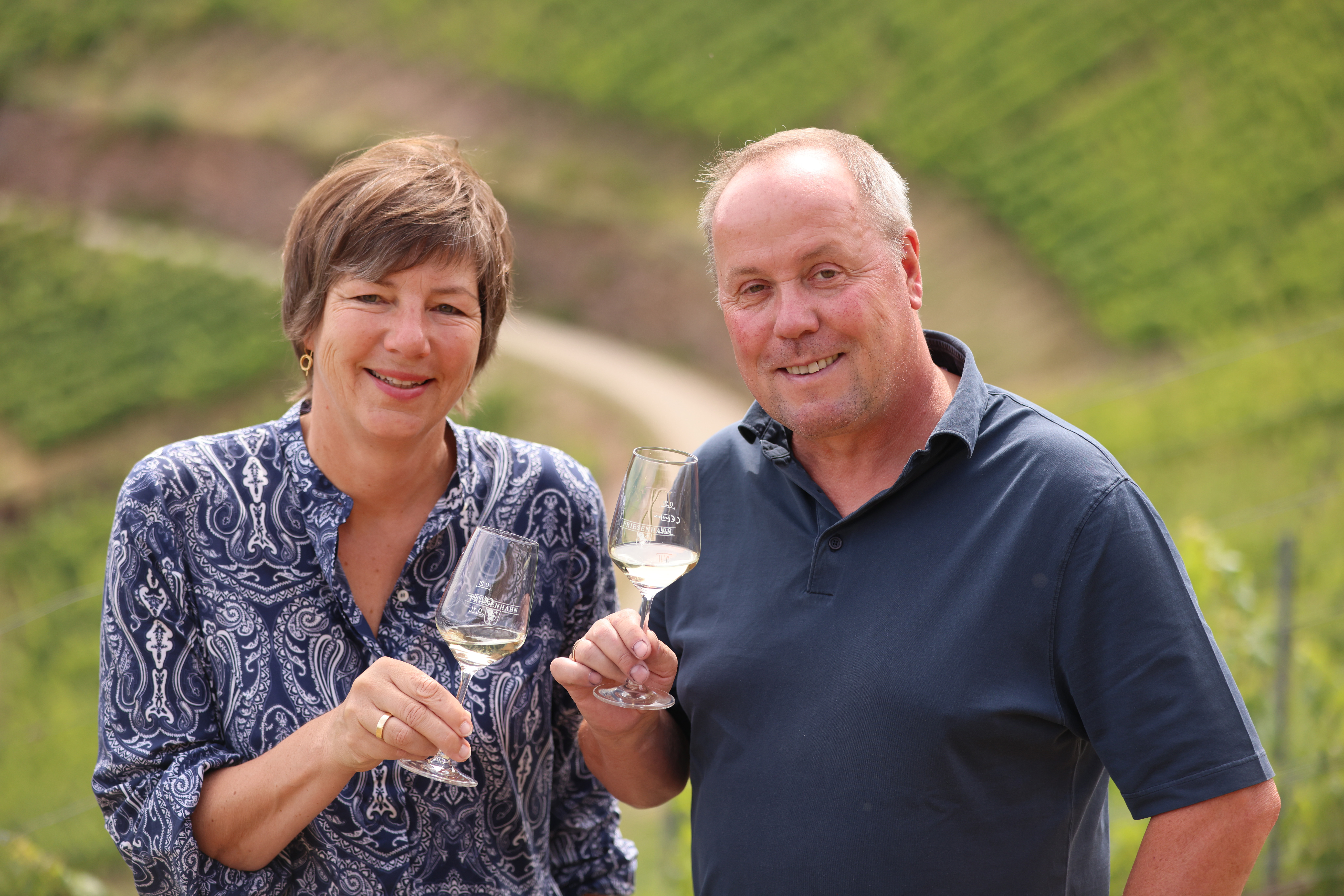 zwei Menschen welche Wein in den Weinbergen trinken und lächeln