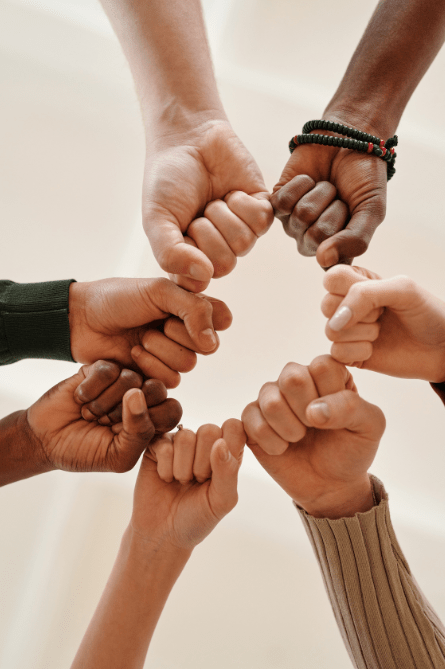 Mehrere Hände, die als Faust im Kreis aneinander treffen, symbolisieren Teamwork und Zusammenarbeit